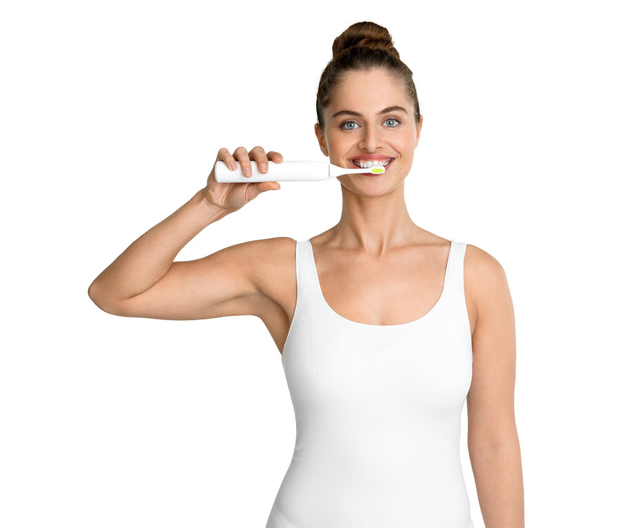 Frau putzt Zähne mit elektrischer Zahnbürste Silk’n »ToothWave©«.