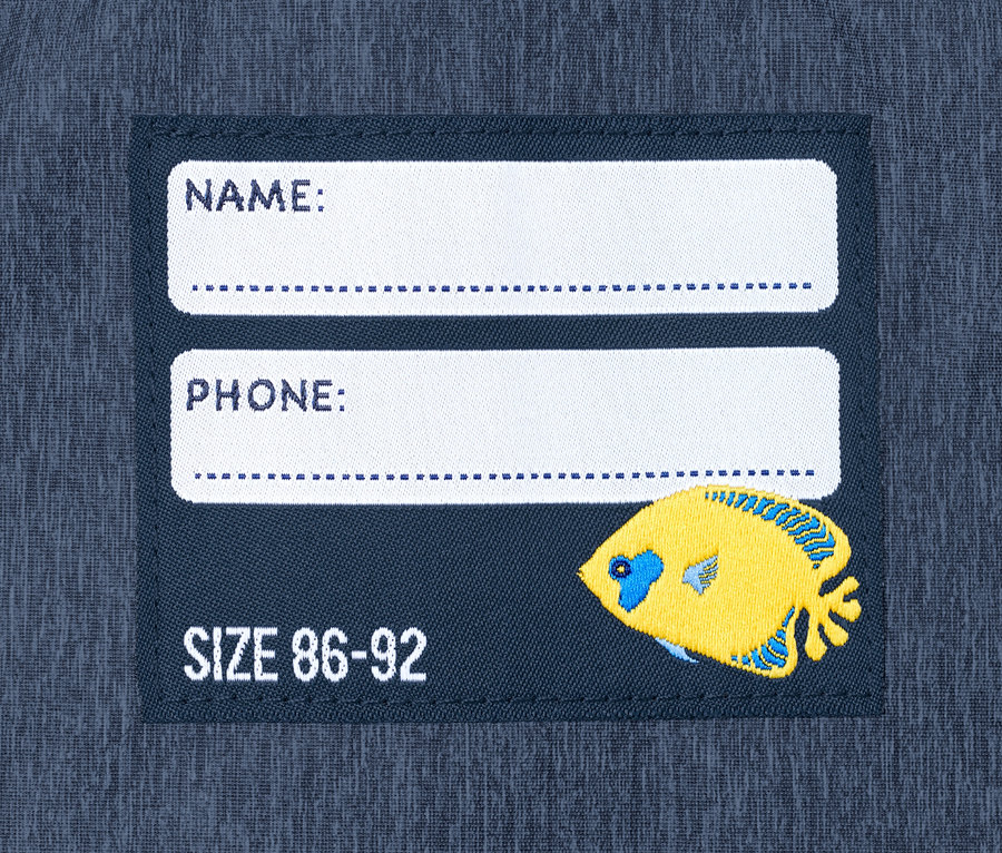 Etikett auf der Regenhose aus recyceltem Material mit Platz für Name, Telefonnummer und Größe 86-92 und einem gelben Fisch.