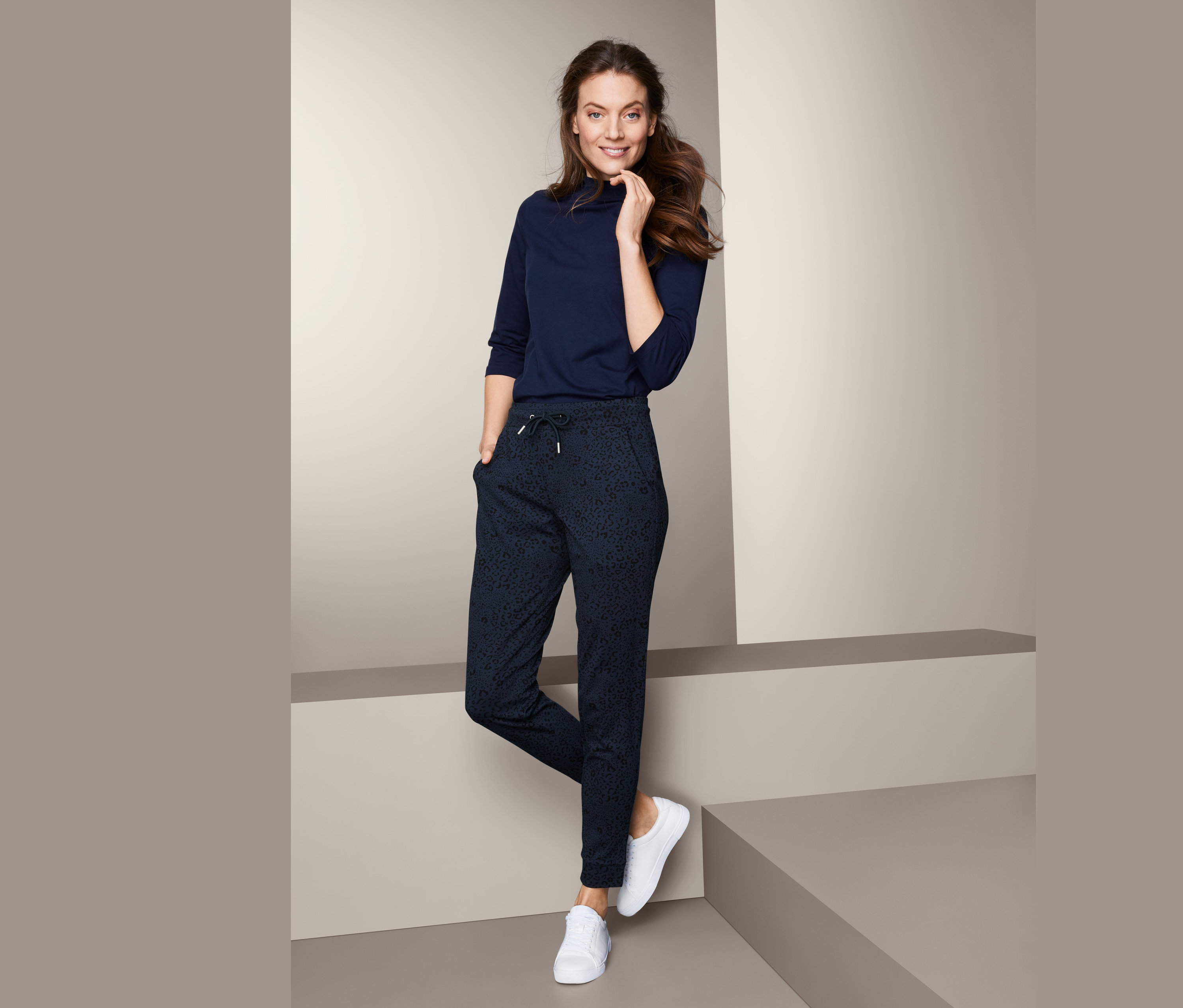 Frau posiert in bedruckter Joggpants und einem Oberteil mit Dreiviertelärmeln.