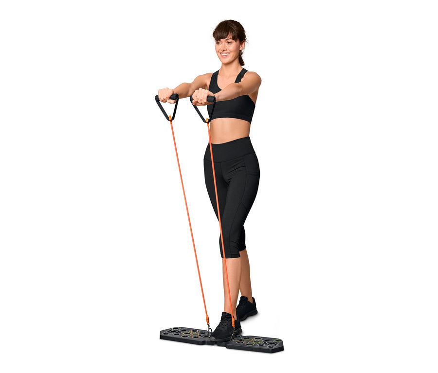 Frau trainiert mit einem Liegestütz-Board mit Elastikbändern.