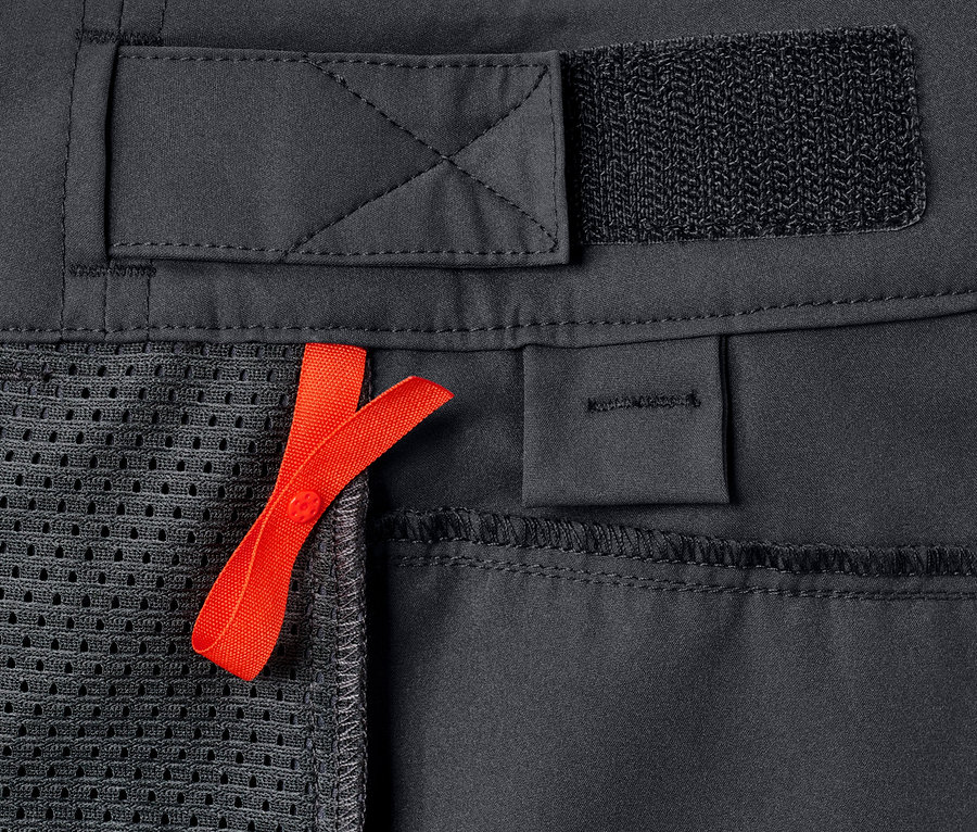 Detailaufnahme der grauen Rad-und-Wander-Shorts »Pro« mit einer orangefarbenen Schleife.