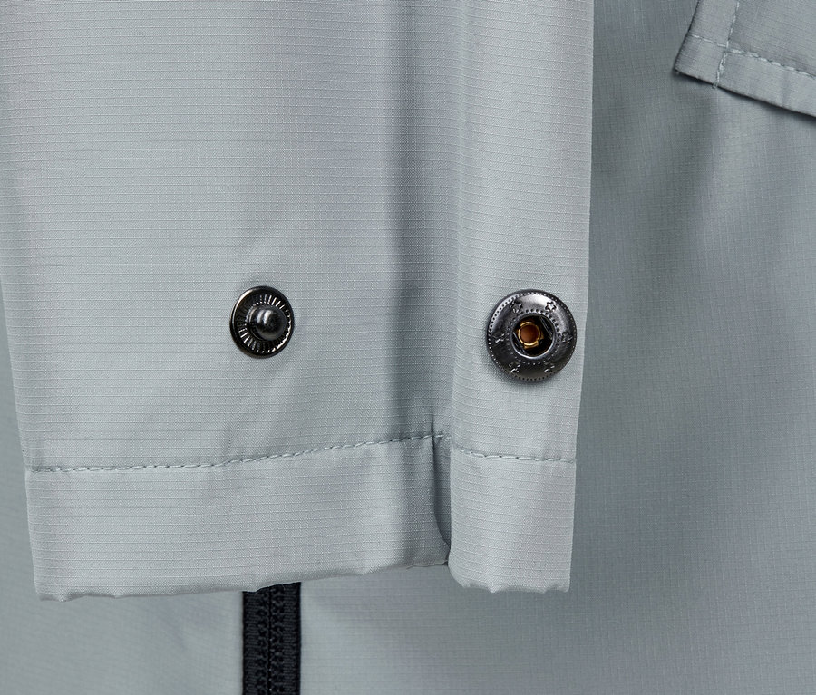 Detailansicht eines grauen Regenjackenponchos mit Metallknöpfen.