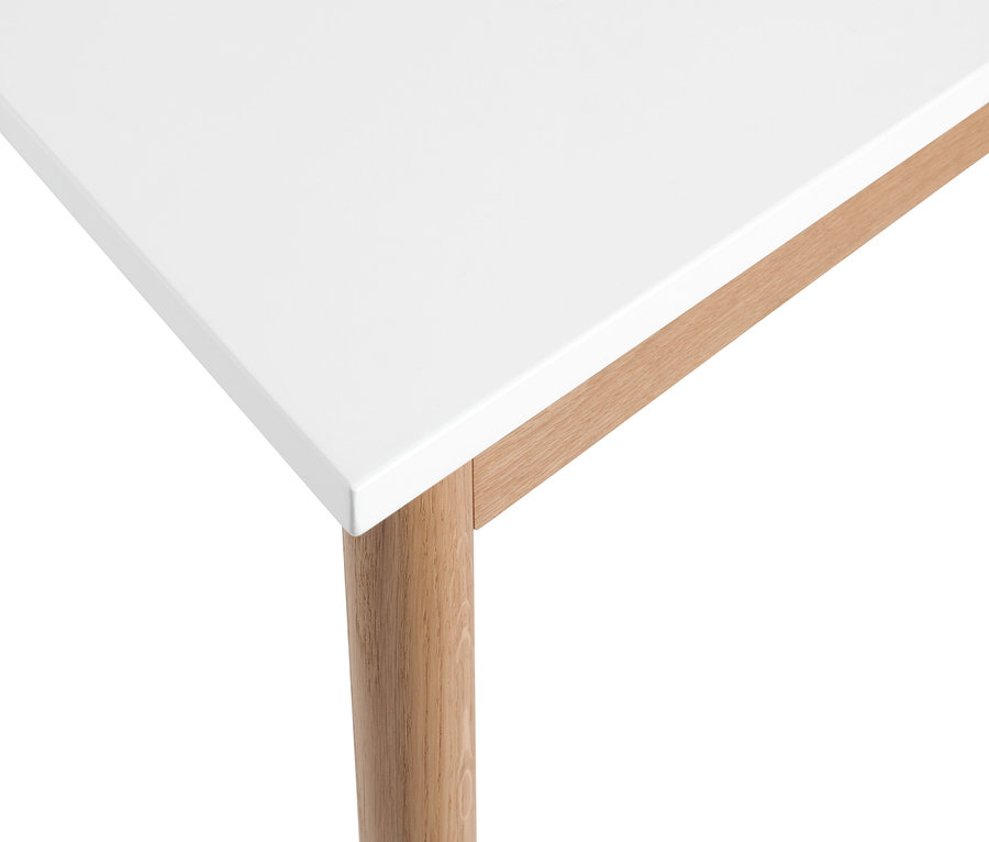 Detailansicht eines weißen trapezförmigen Schreibtisches mit Holzbeinen.