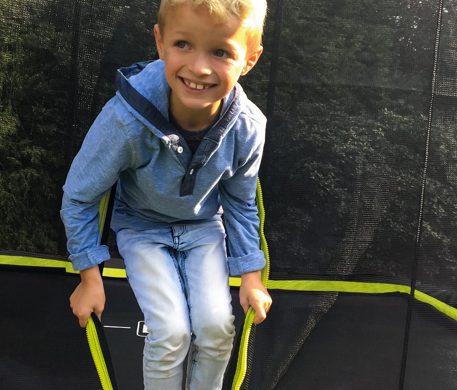 Blonder Junge sitzt auf dem EXIT Bodentrampolin »Silhouette«, ca. 214 x 305 cm.