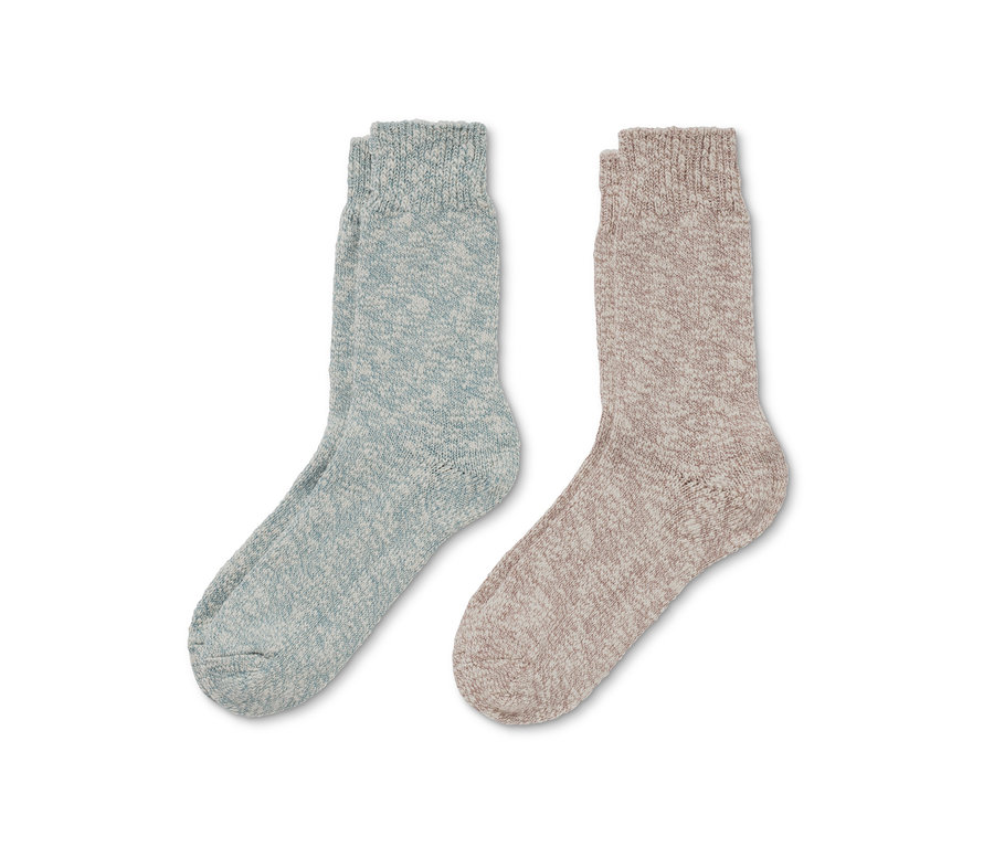 Zwei Paar Stricksocken liegen nebeneinander. Ein Paar ist hellblau, das andere beige.