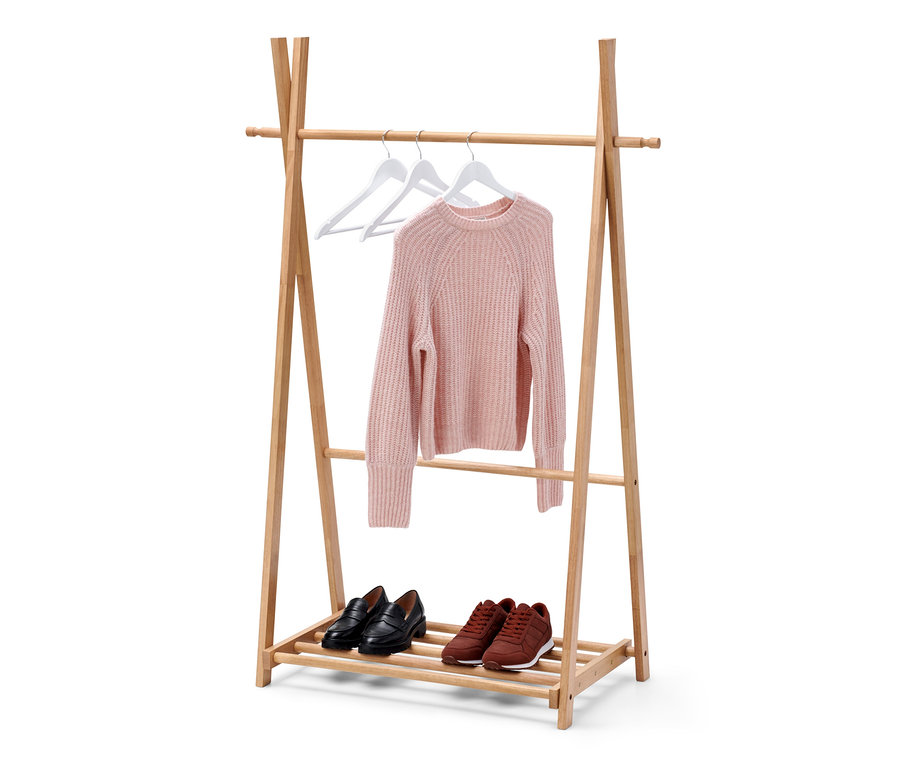 Ein Pullover hängt auf zwei weißen Kleiderbügeln auf einem hölzernen Kleiderständer. Auf dem unteren Regal befinden sich schwarze Slipper und braune Turnschuhe.