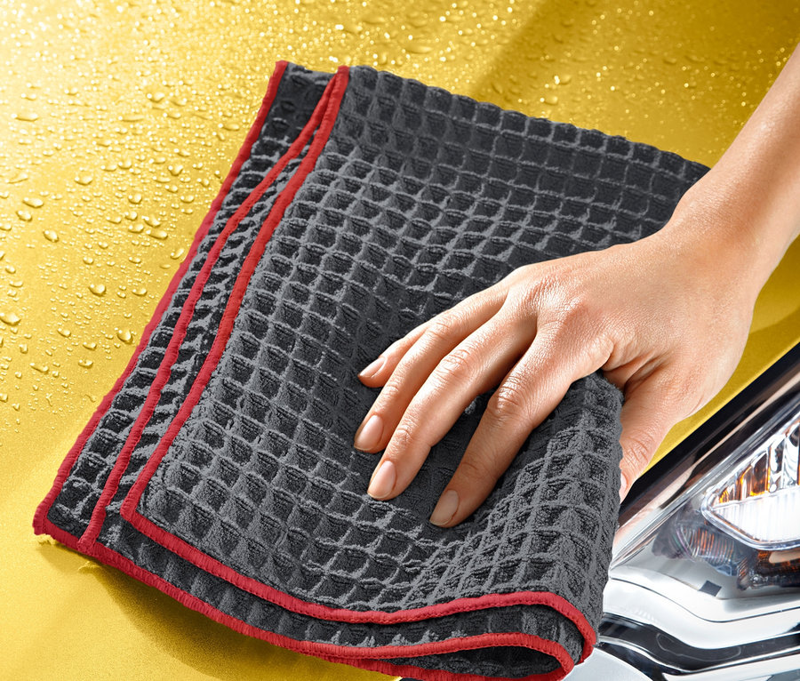 Hand trocknet gelbe Motorhaube mit Spezial-Trockentuch.