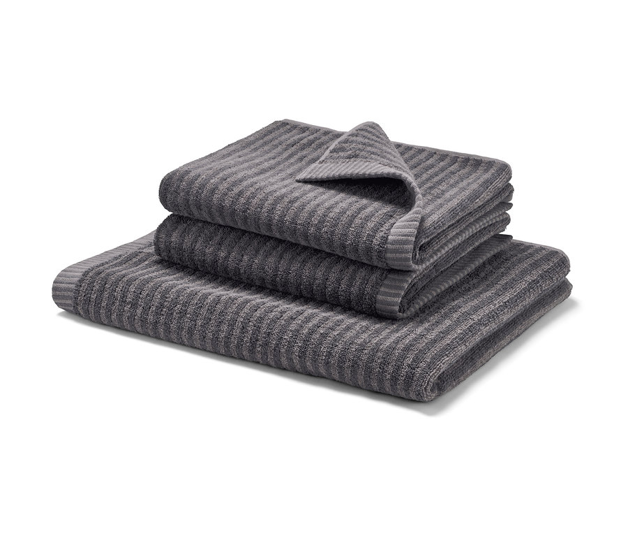 Gestapeltes graues Badetuch und zwei anthrazitfarbene Handtücher.