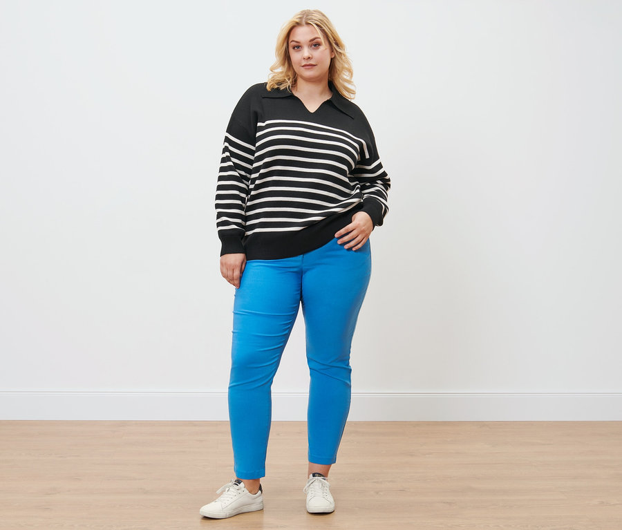 Frau posiert in einem Pullover mit Kragen und einer Bengalin-Hose.