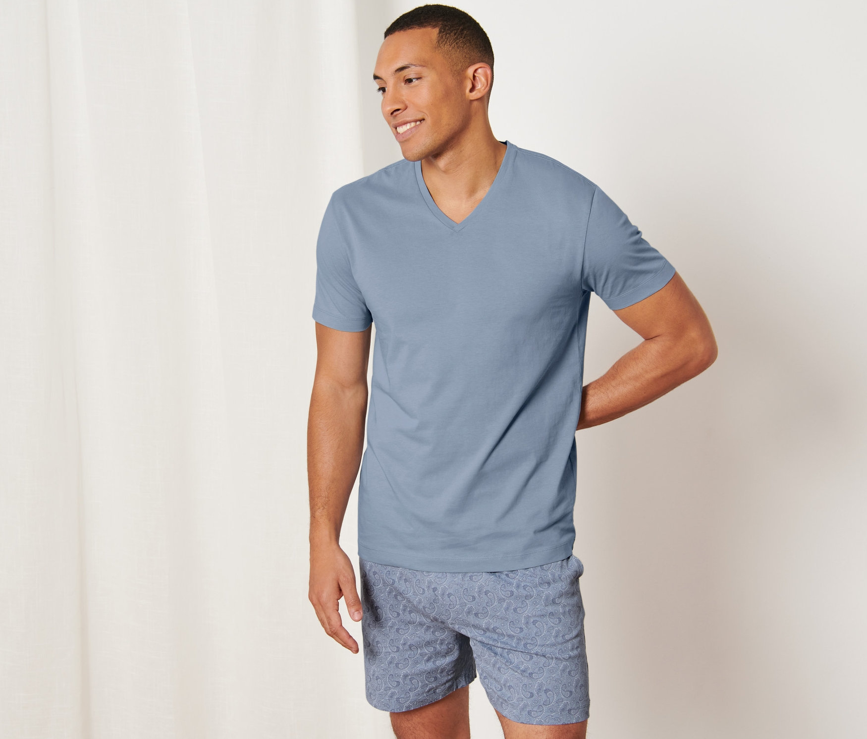 Mann posiert in Shorty-Pyjama mit Alloverprint.