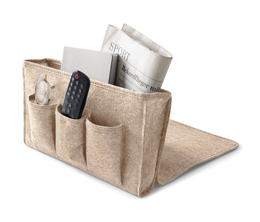 Ein beiger Bett- und Couchorganizer mit Buch, Zeitung, Brille und Fernbedienung.