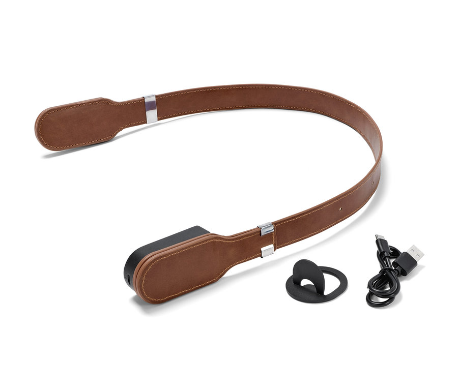 Eine braune Leselampe mit magnetischem Clip-System liegt auf einem weißen Hintergrund neben einem schwarzen Magnet und einem Ladekabel.