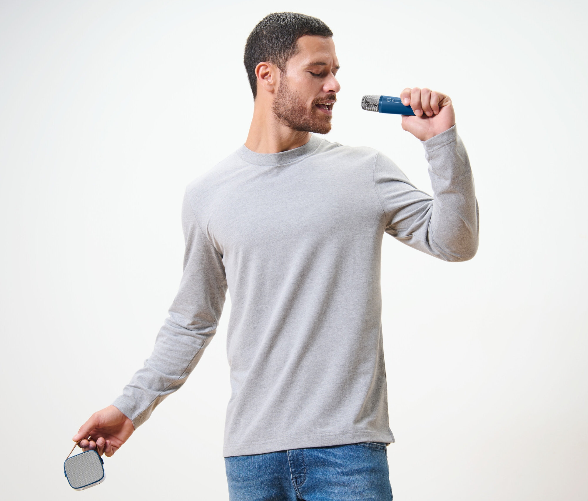 Mann singt in ein Mikrofon aus einem Karaoke-Set mit Lautsprecher.