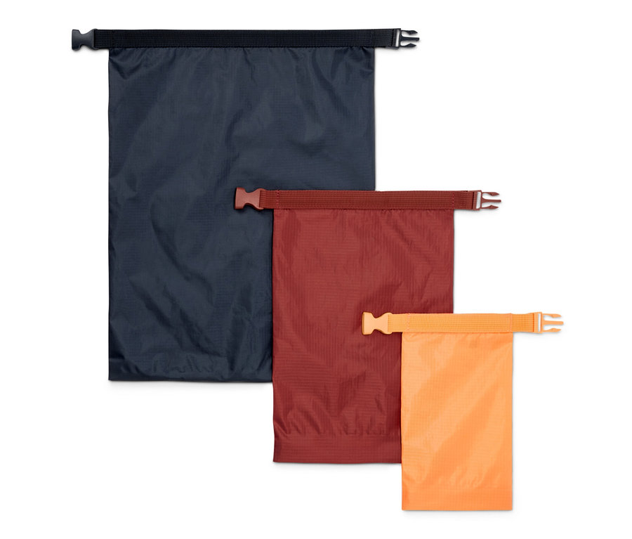 Drei wasserfeste Packsäcke in Blau, Braun und Orange.