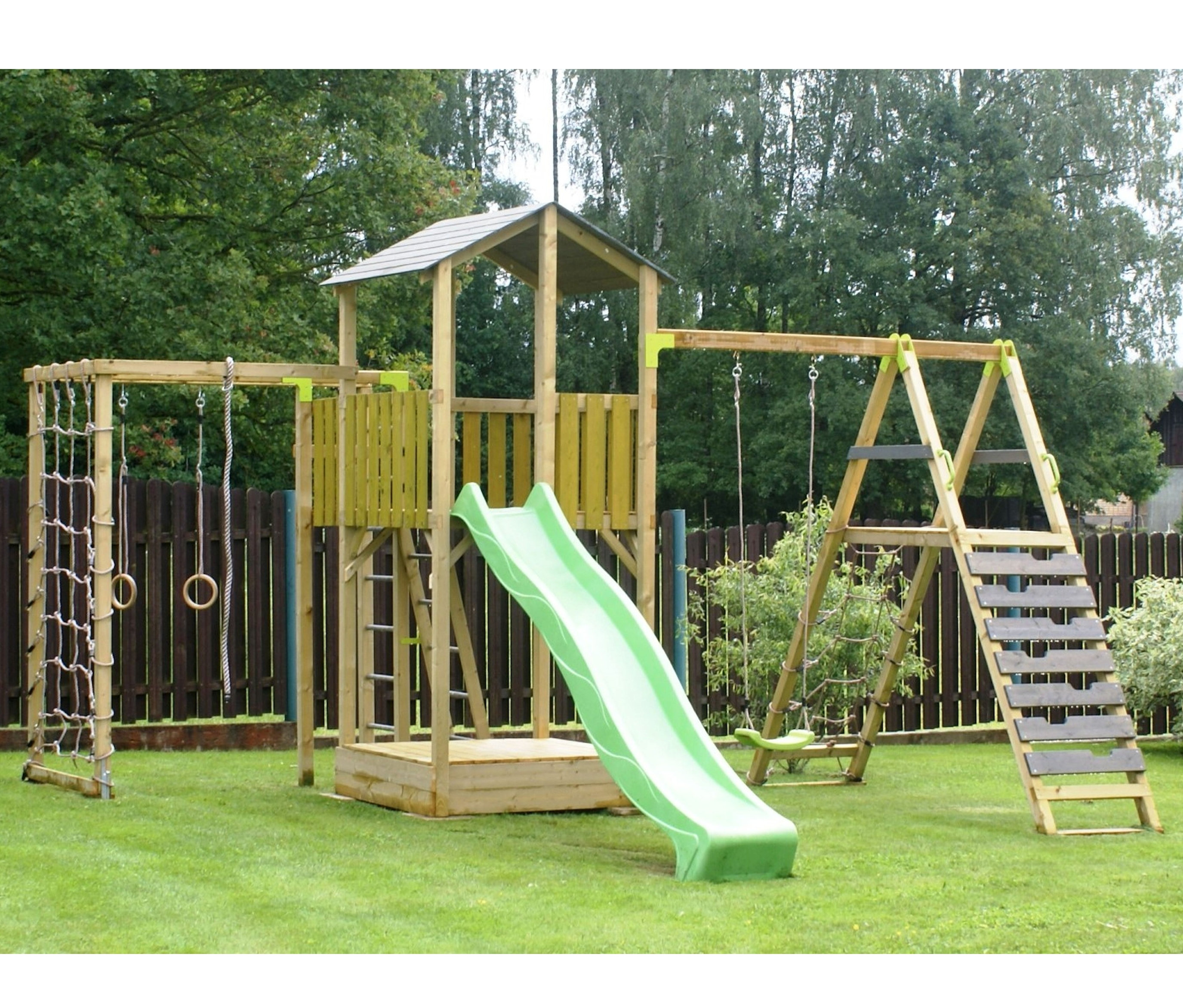 Wendi Spielplatz »Dino« mit Rutsche, Schaukel und Kletterwand steht auf einer Wiese.