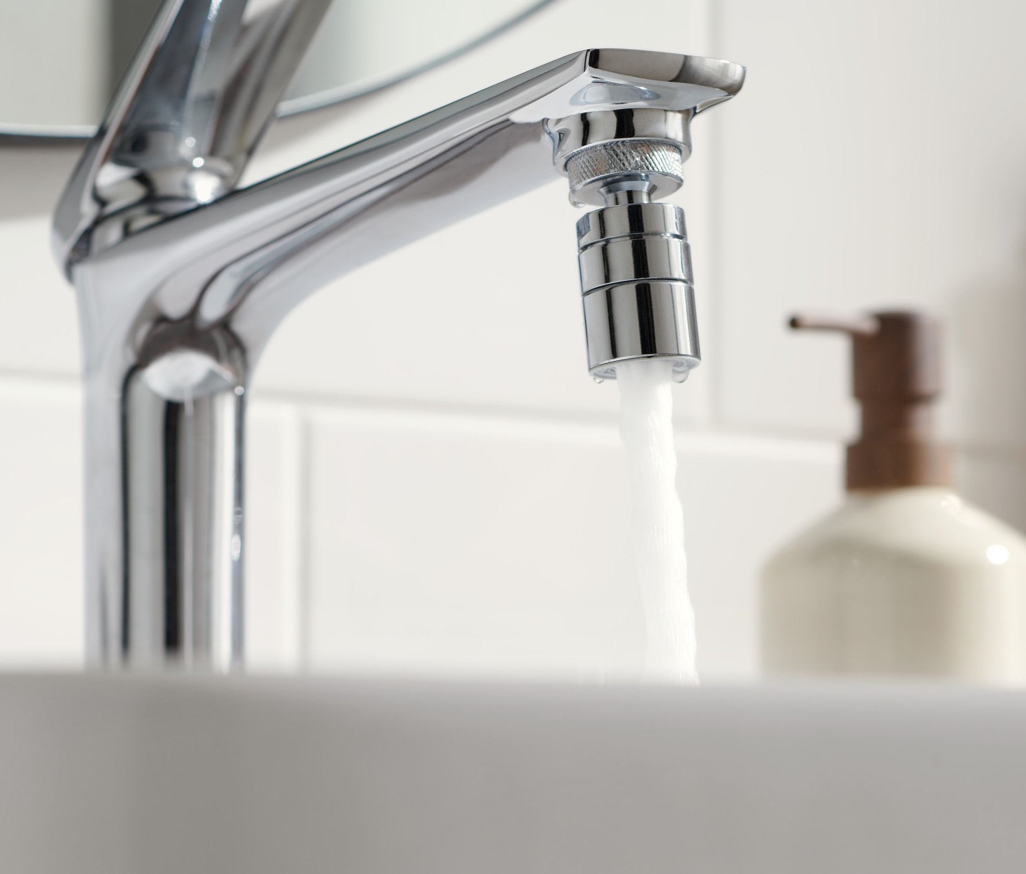 Wasser fließt aus einem Wasserhahn mit wassersparendem Wasserhahn-Aufsatz.