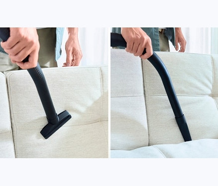Mann saugt Couch mit Bosch Bodenstaubsauger BGD38RD1H.