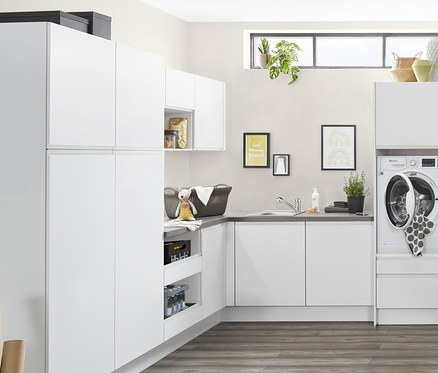 Funktionale Waschküche mit weißen Schränken, Waschmaschine, Trockner und Wäscheständer.