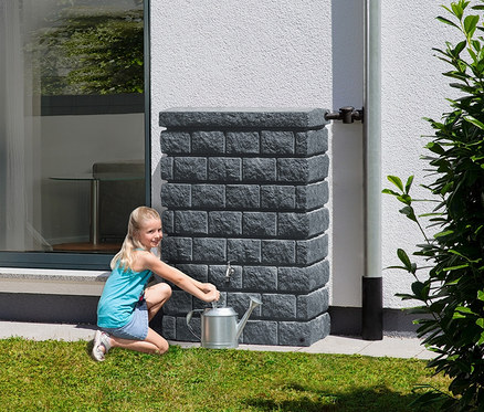 Mädchen schöpft Wasser aus dem graphit-grauen Garantia Wandtank-Komplett-Set »ROCKY Junior«, ca. 300 l, in eine silberne Gießkanne.