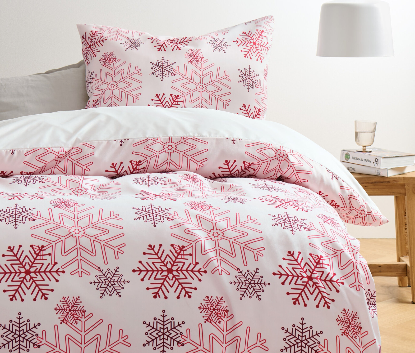 Ein Bett mit weißer Microfaser-Flanell-Bettwäsche mit roten und lila Schneeflocken.