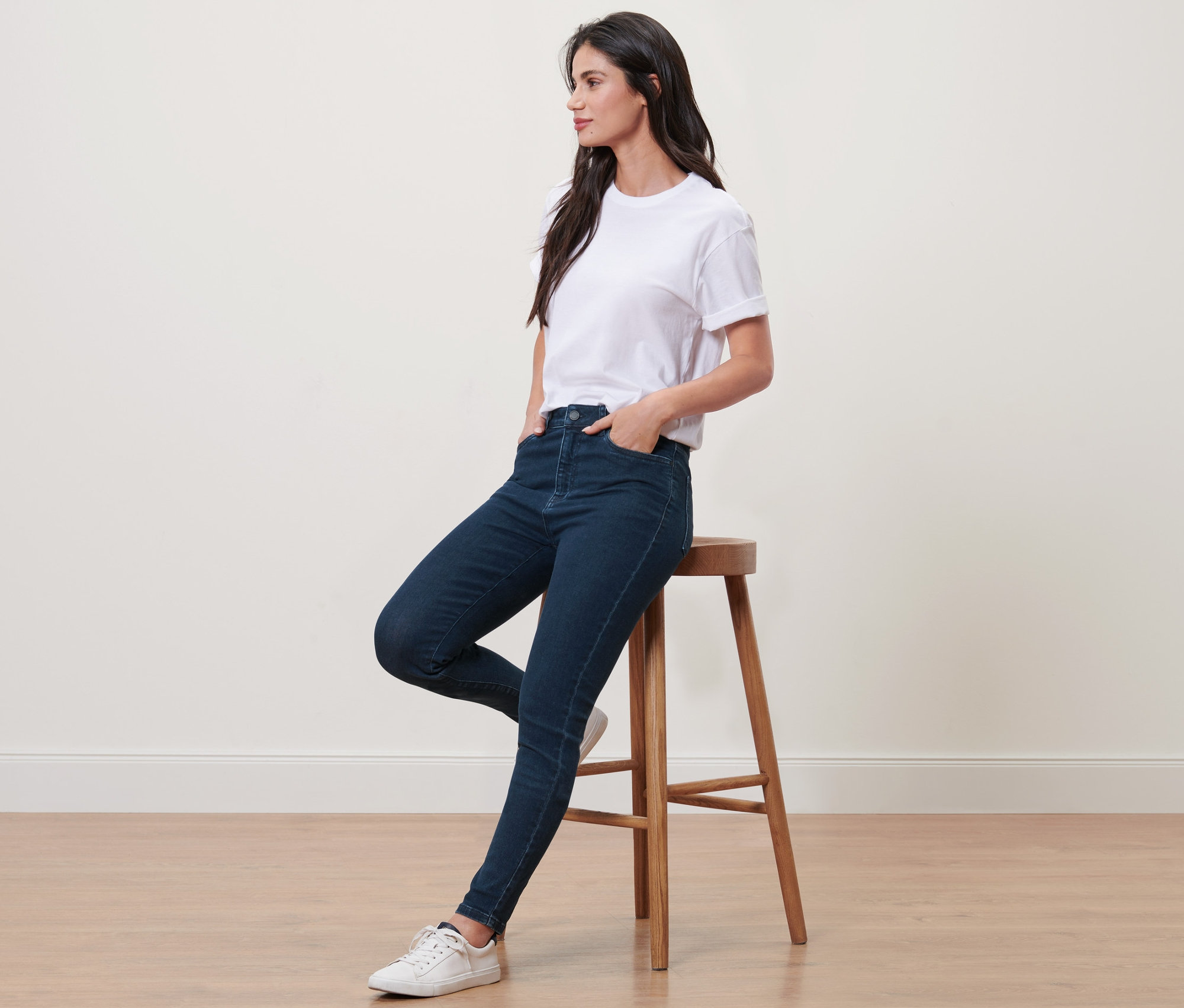 Frau sitzt auf einem Hocker und trägt eine Skinny-Denim »Fit Hanna« und ein weißes T-Shirt.