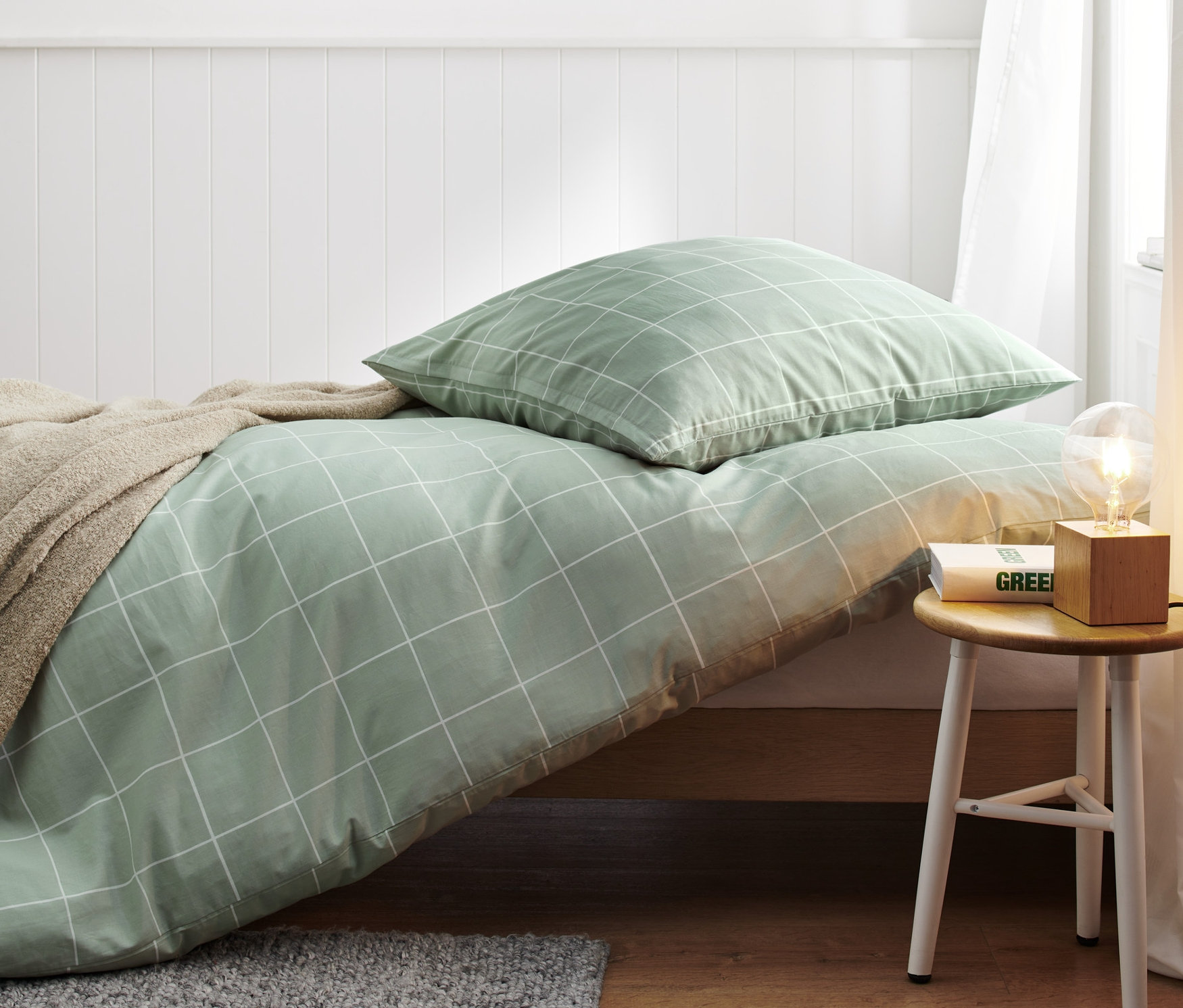 Grüne Premium-Baumwoll-Bettwäsche in Normalgröße mit weißem Gittermuster auf einem Bett.