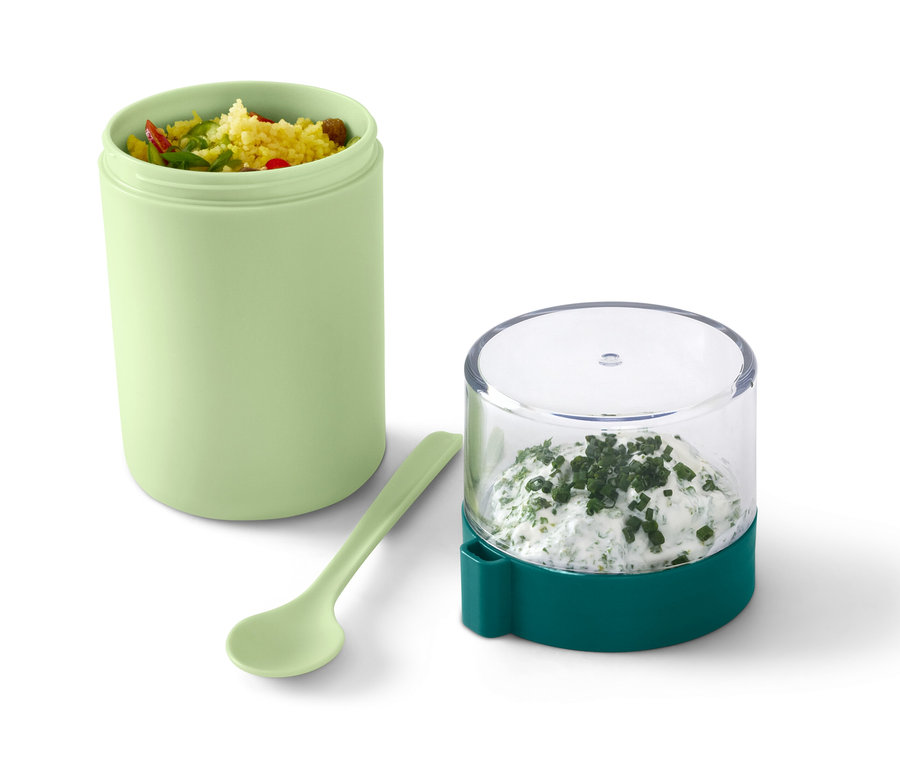 Ein grüner To-go-Joghurt-Becher mit Inhalt, daneben ein Löffel und ein Behälter mit Kräuterquark.