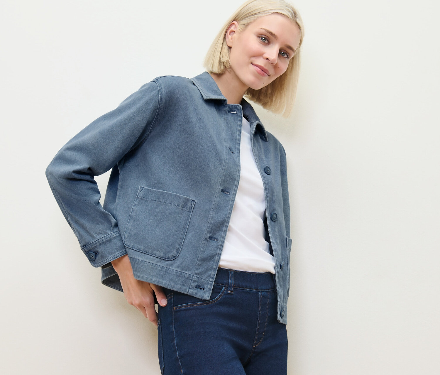 Blonde Frau posiert in Jeans und Jeans-Jerseyjacke.