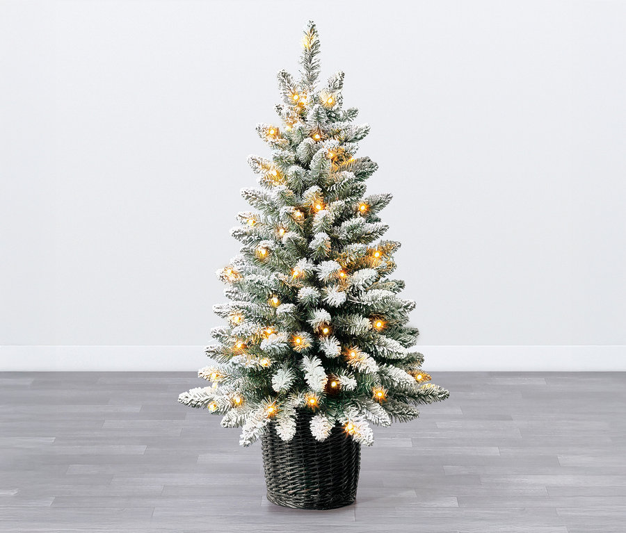 Ein Evergreen LED-Weihnachtsbaum mit geflochtenem Übertopf, ca. 90 cm, steht auf einem grauen Holzboden vor einer weißen Wand.
