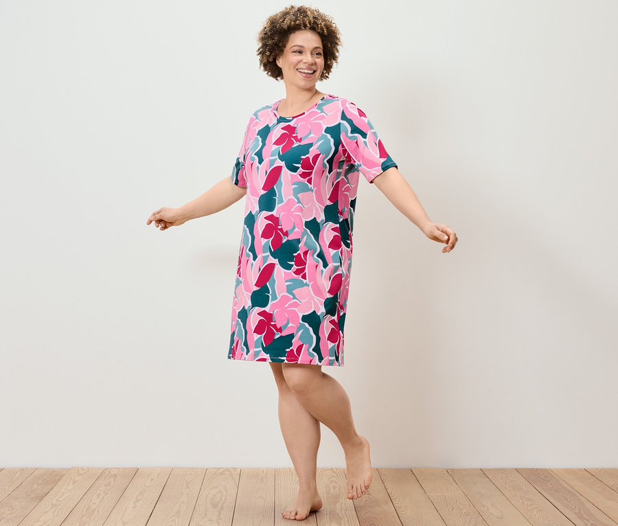 Frau tanzt in einem Nachthemd mit Blumenmuster.