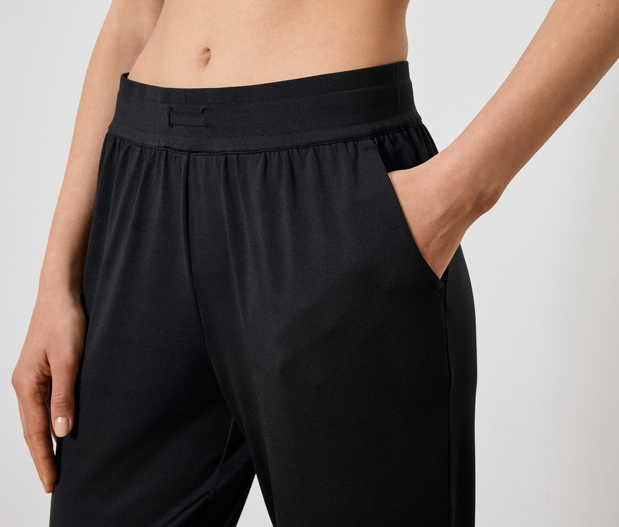 Frau hat Hand in der Tasche einer schwarzen Hose.