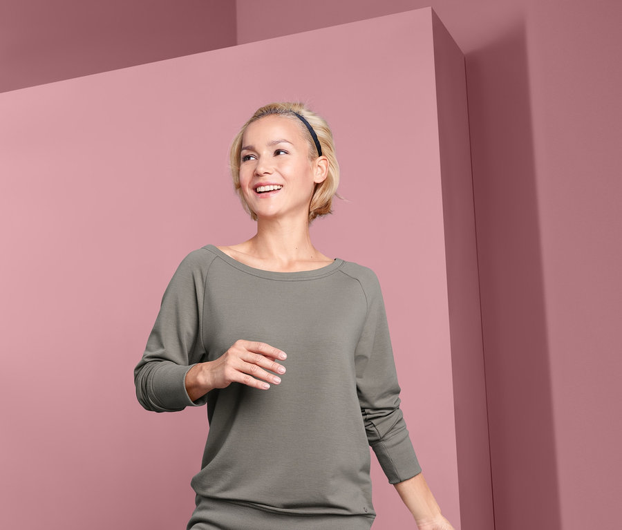 Frau in Baumpose mit Yogasweatshirt.