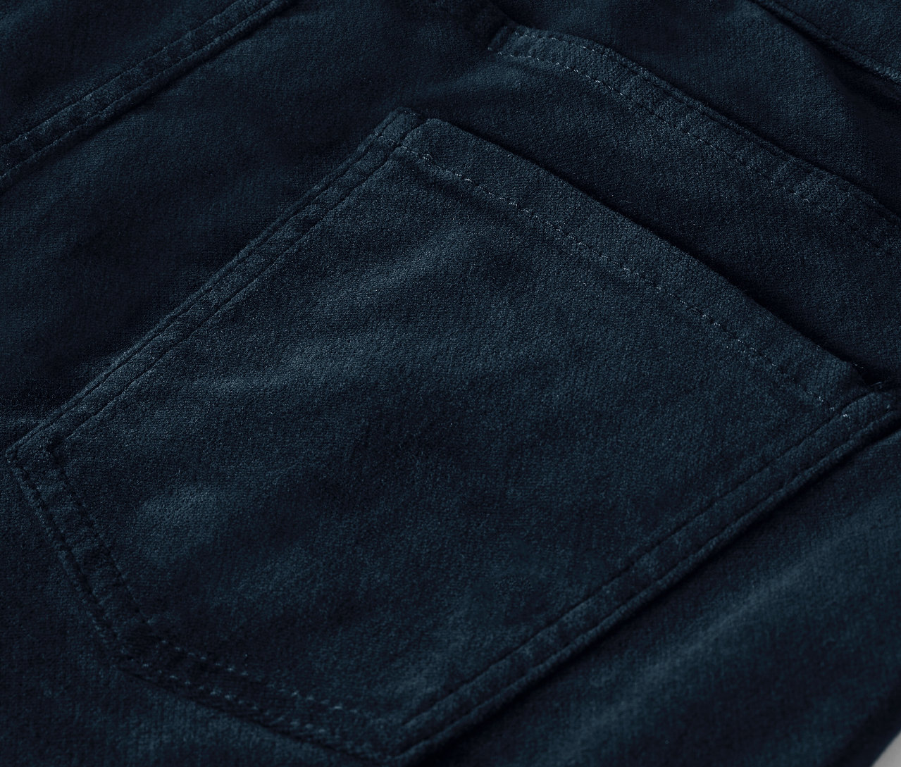 Detail einer Gesäßtasche einer dunkelblauen Cordhose.