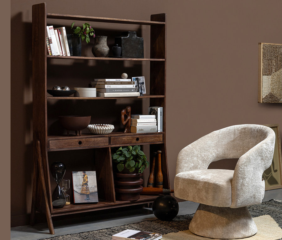 Woood Schrank »Sivian« mango nussbaum steht neben einem beige Sessel in einem Raum.