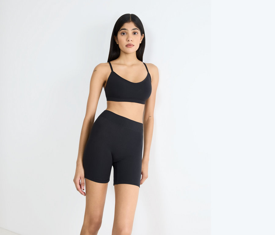Frau posiert in schwarzem Sport-BH und Shorts.