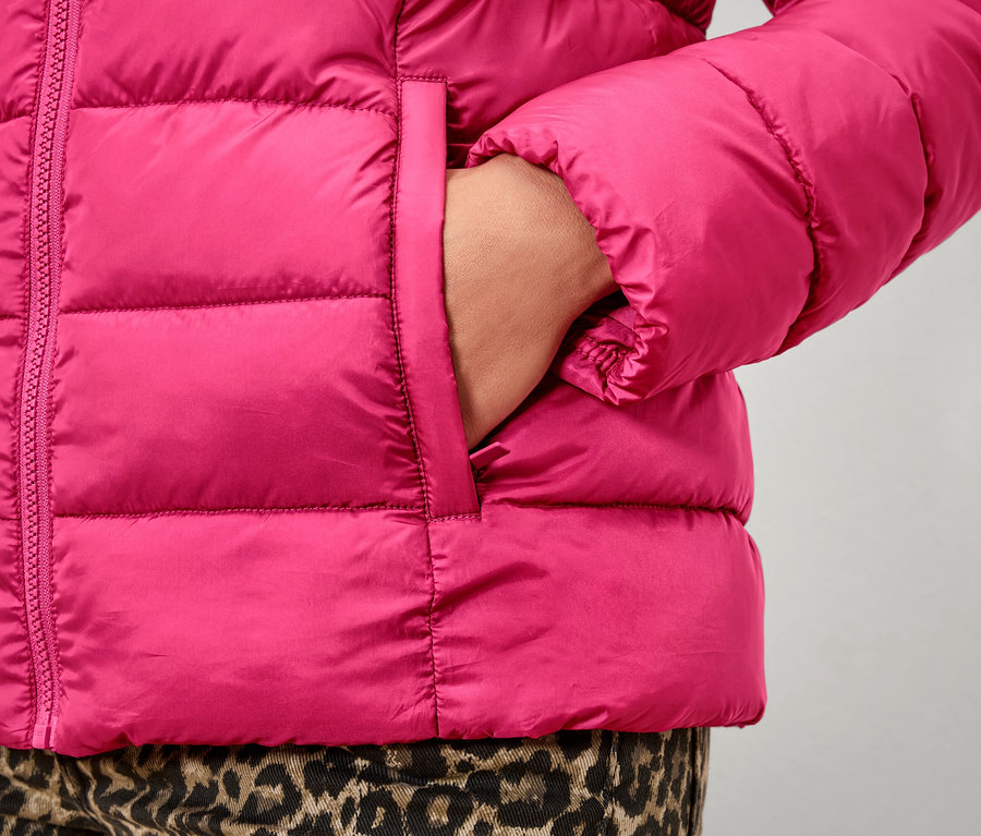 Detailaufnahme einer pinken Steppjacke mit einer Hand in der Tasche.