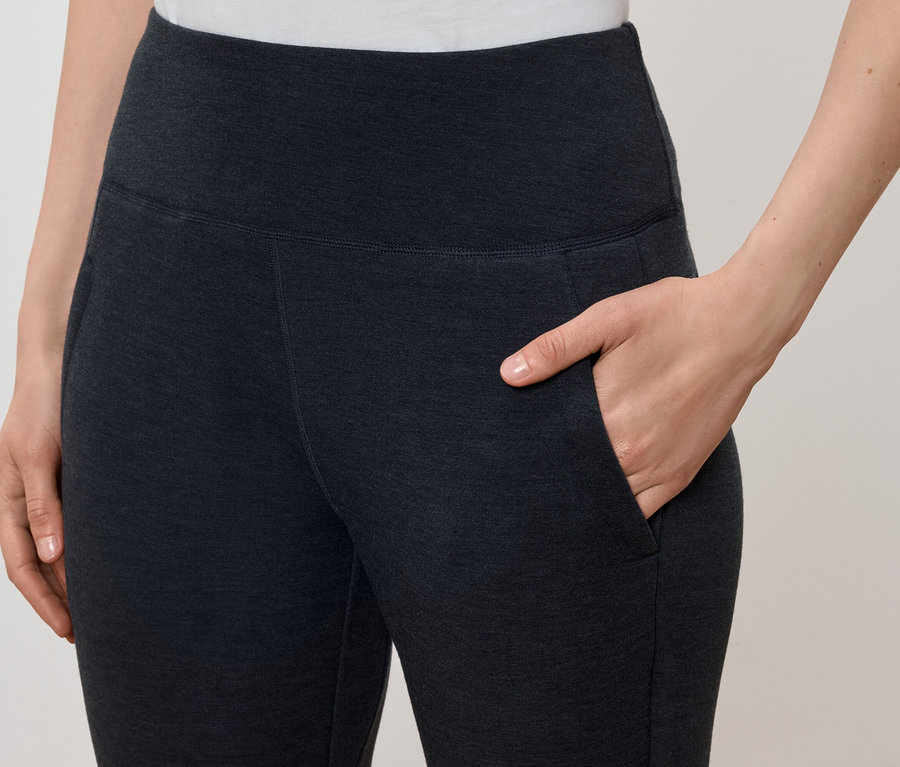 Frau hat ihre Hand in der Tasche einer dunkelgrauen Leggings.