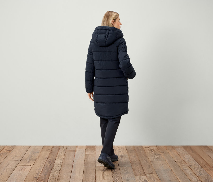 Frau trägt dunkelblaue Steppjacke mit Kapuze, von hinten gesehen.