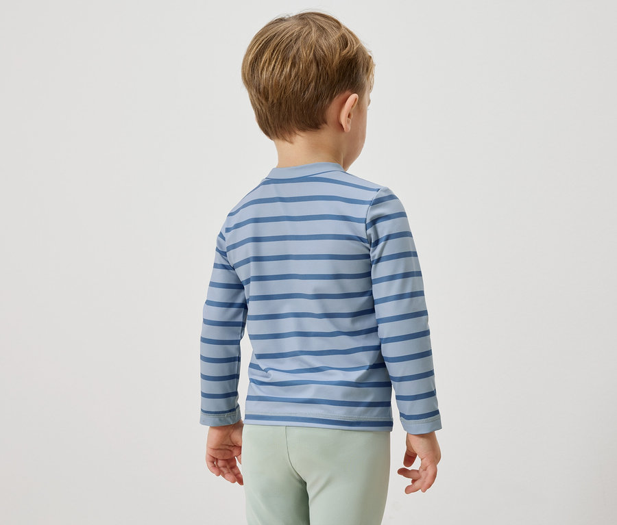 Ein Kind von hinten, es trägt ein blau gestreiftes Langarmshirt und hellgrüne Hosen.