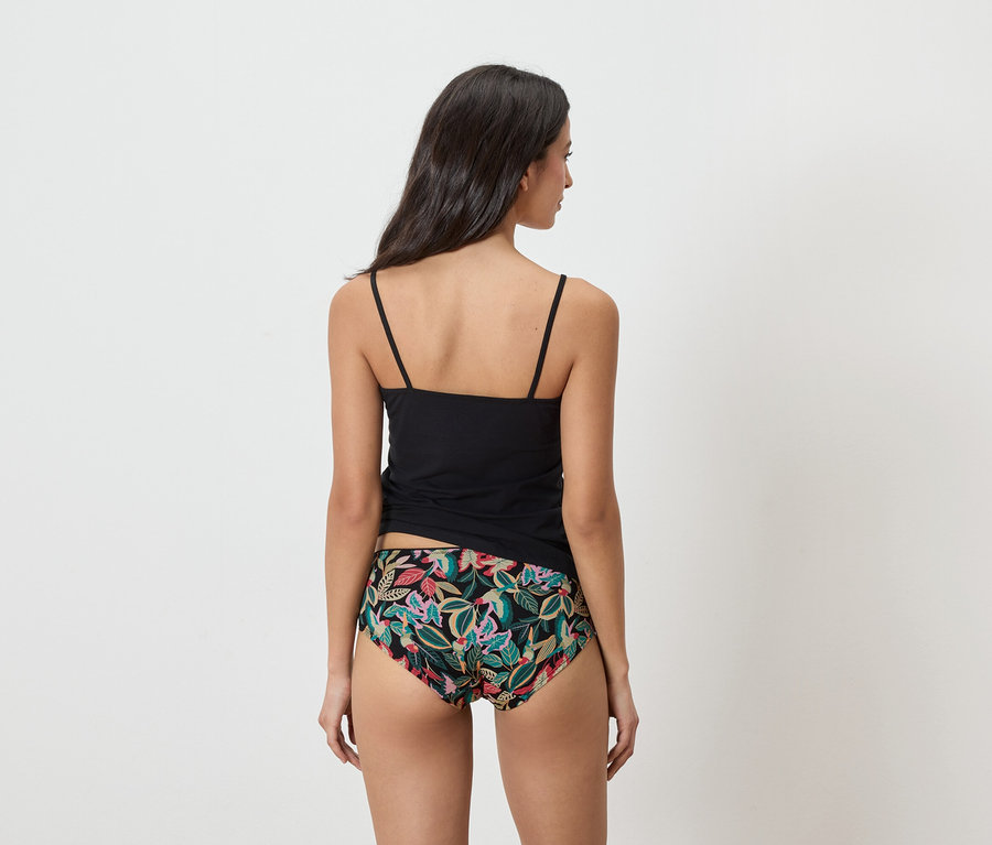Frau von hinten, die ein schwarzes Top und eine Unterhose mit Blumenmuster trägt.