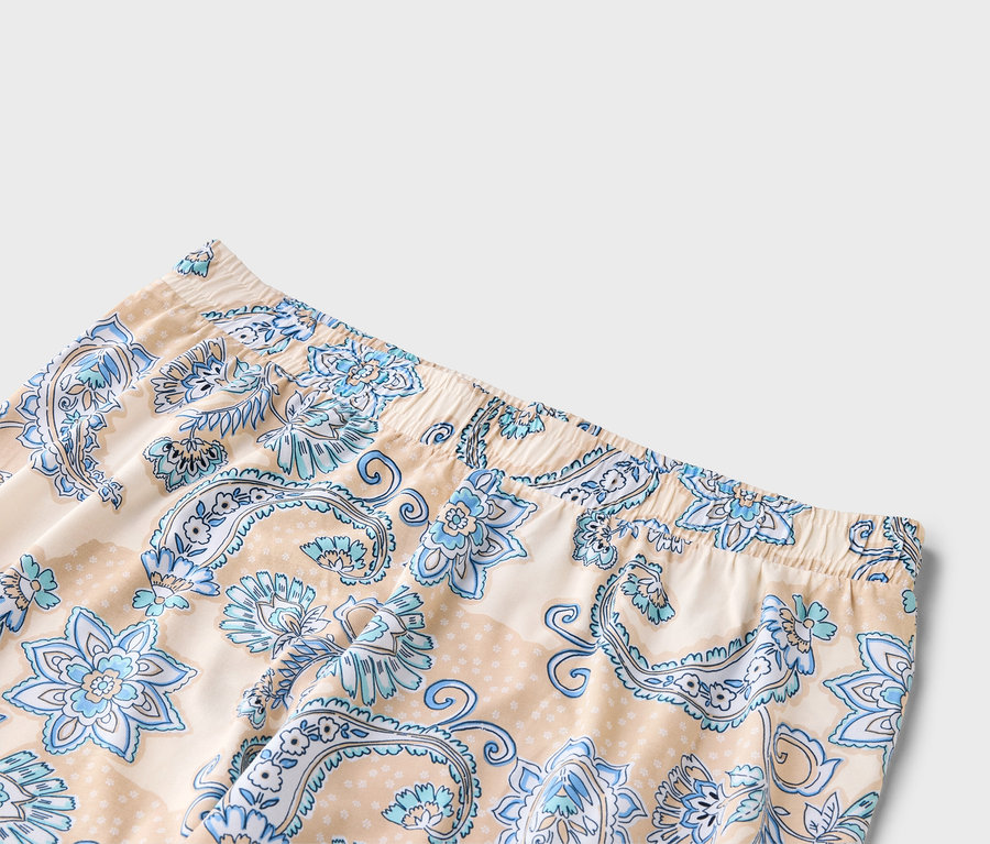 Nahaufnahme von beigen Hosen mit blauem Blumenmuster und elastischem Bund.