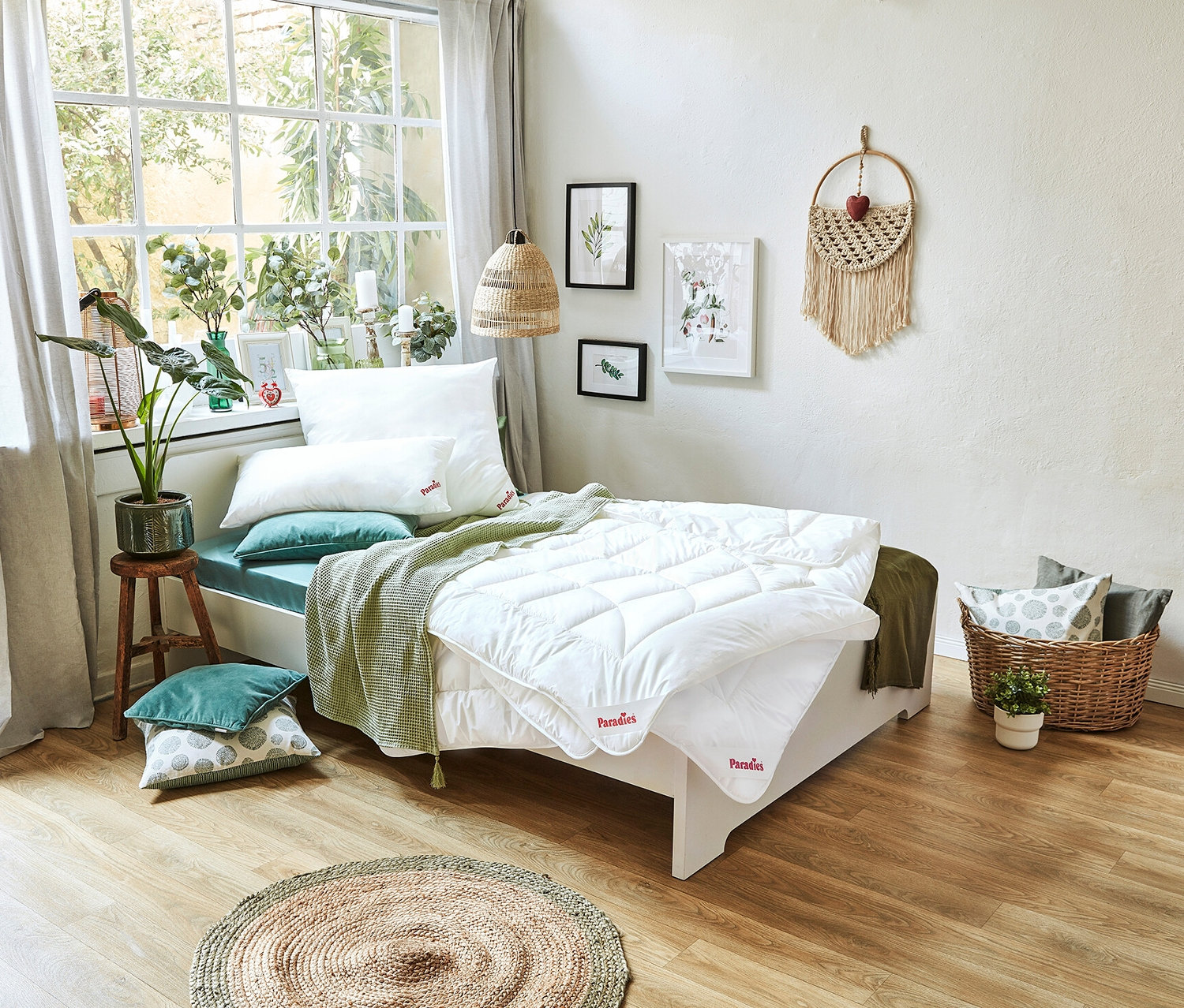Ein Bett mit einer weißen Paradies Sommerdecke »BestCool« in Normalgröße und Übergröße, Kissen und einer grünen Decke steht vor einem Fenster.