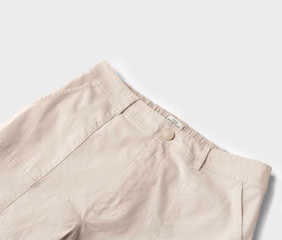 Nahaufnahme einer beigen Hose mit Knopf und Taschen.