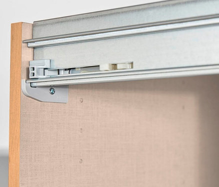 Nahaufnahme einer Schubladenschiene aus Metall, die an einer beigen Schubladenseite befestigt ist.