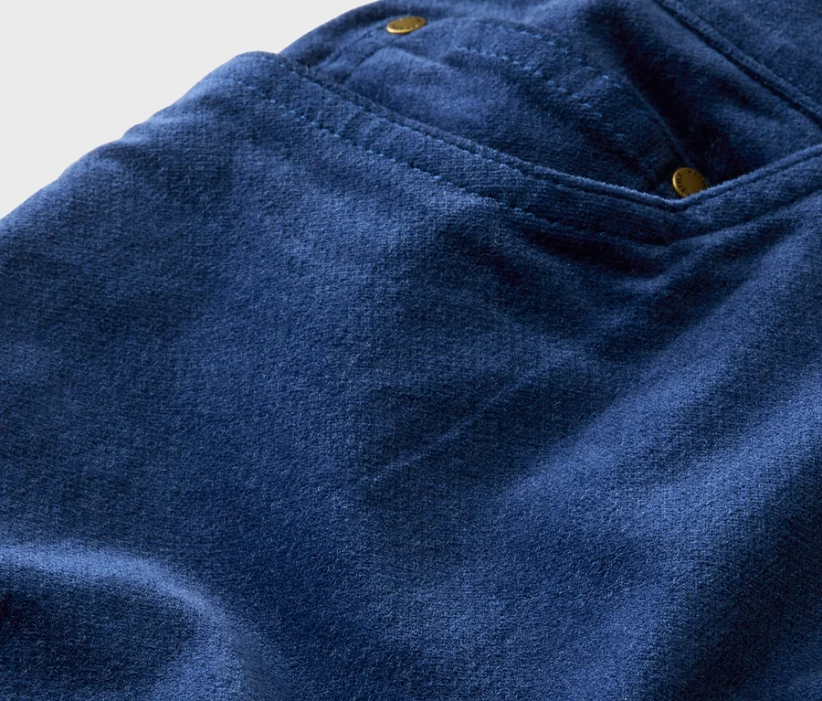 Nahaufnahme von marineblauen Hosen mit einer kleinen Tasche, die mit goldenen Nieten befestigt ist.