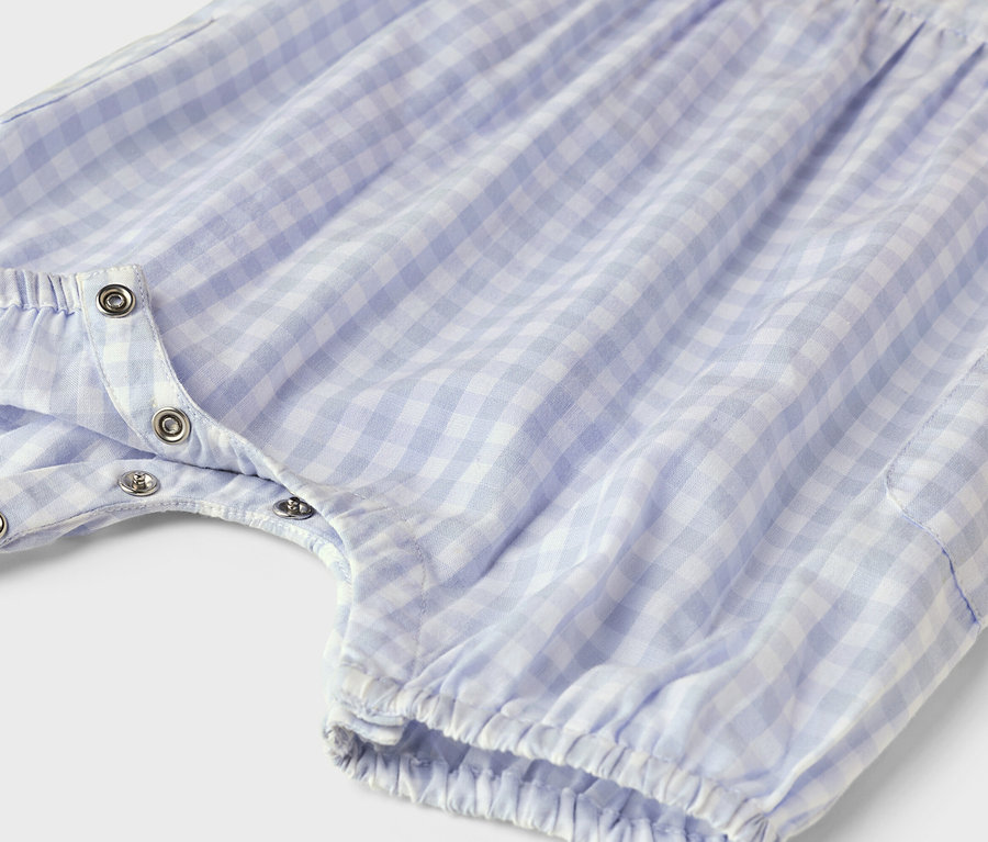 Nahaufnahme eines blau-weiß karierten Baby-Stramplers mit Druckknöpfen.
