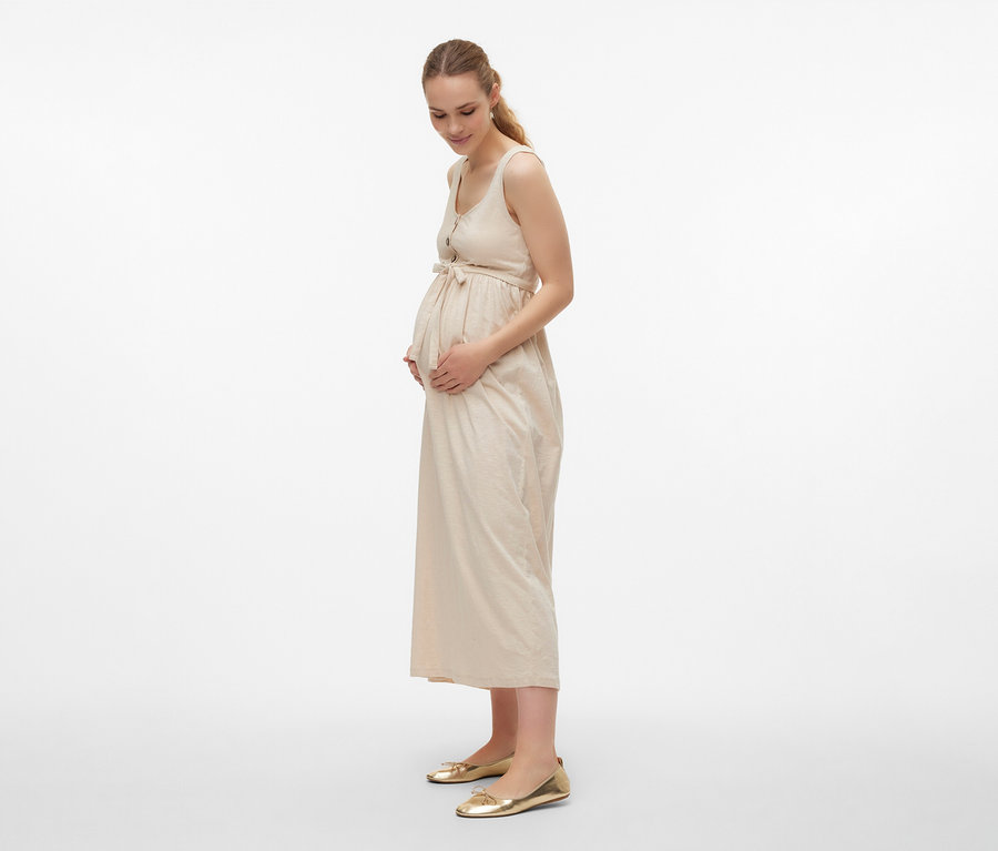 Schwangere Frau im MAMALICIOUS »MLEVI LIA« Kleid mit Gürtel und goldenen Schuhen.