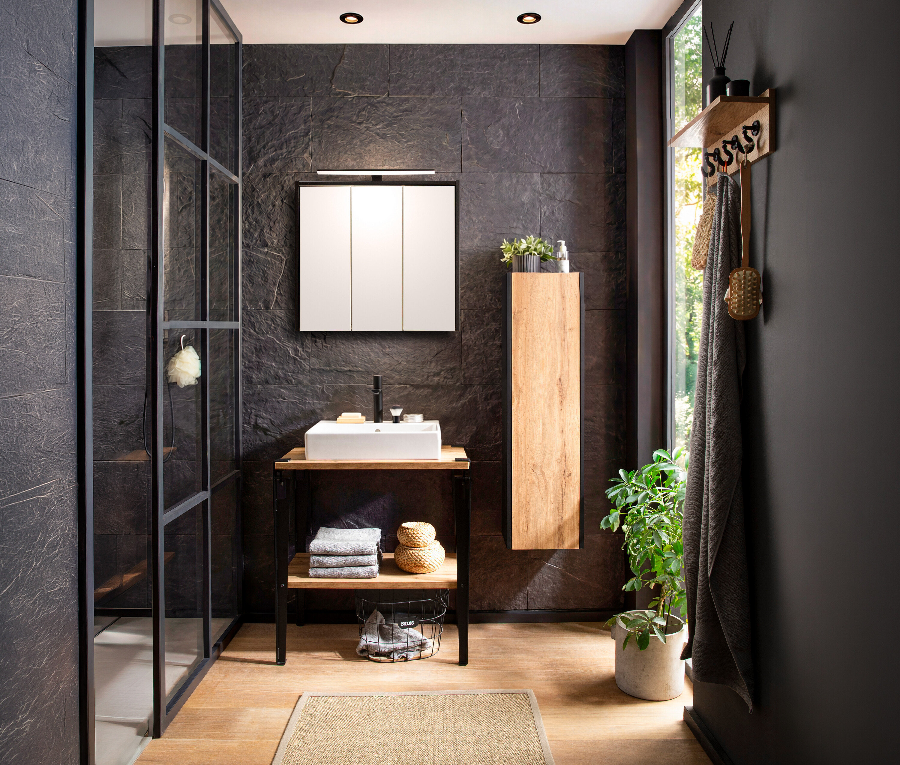 Badezimmer mit WS Waschtisch »Tonder« im Dekor Eiche Landhaus und WS Highboard »Tonder« im Dekor Eiche Landhaus neben einem Fenster.