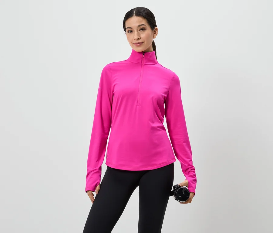 Frau in pinkem Langarmshirt mit Reißverschluss und schwarzen Leggings, hält eine Wasserflasche vor einem weißen Hintergrund.
