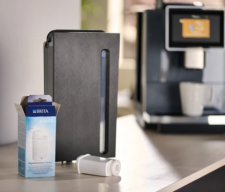 Eine Packung Brita AquaAroma Crema Filter neben einem Filter und einer Kaffeemaschine.
